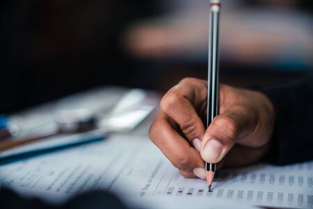 Hand of Student doing test or exam  in classroom of school with stress.Low key styleの写真素材