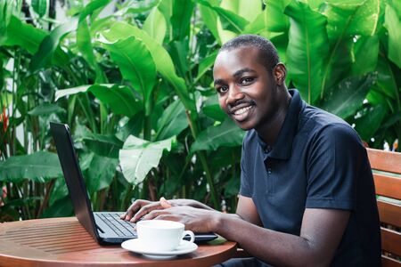 African man using a laptop computer outside a coffee cafeの写真素材
