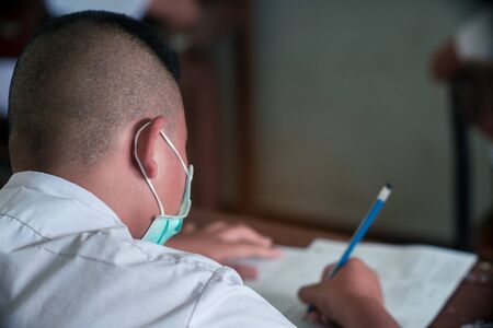 Students wearing mask for protect  corona virus or covid-19 and doing exam answer sheets exercises...