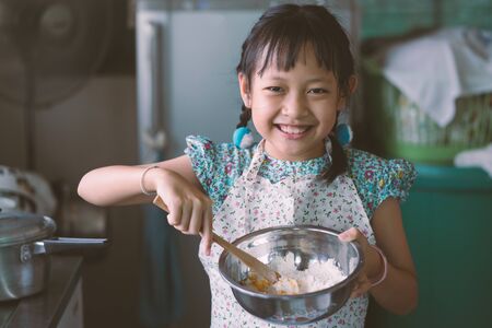Little Child girl  wear apron and learning about cooking lunch in a kitchen.Vintage styleの写真素材