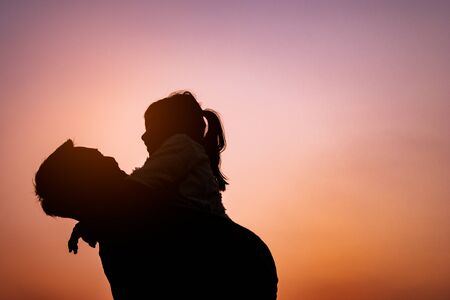 Smile daughter and his father are playing and hugging outdoors.  Silhouette color styleの写真素材