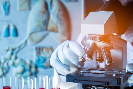 Close up to microscope examining of test sample in laboratory with Medical or doctor looking...