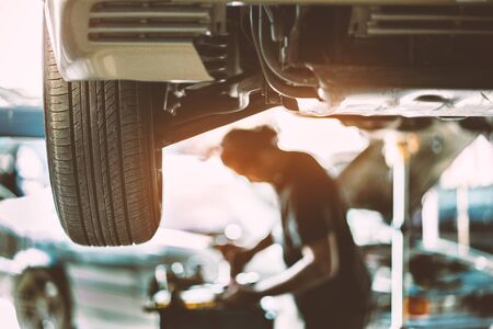 Wheel of car in automobile service with mechanic checking it at in the garage