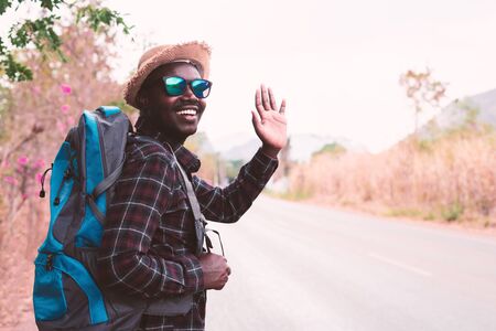 African man traveler carrying backpack walking on the highway roadの写真素材