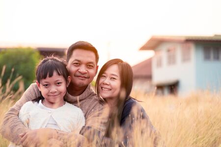 Happy family Father mother and daughter sitting and hugging together on a meadowの写真素材