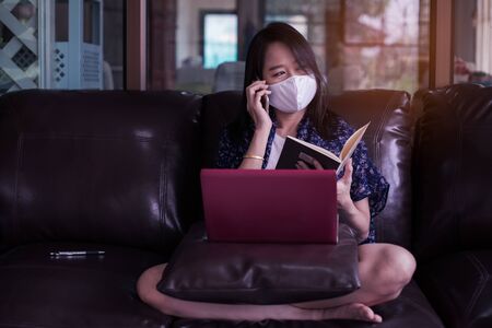 Woman working on laptop at home with wear medical face mask for protect for protect 2019 - nCov , covid 19 or corona virus.WFH or Working from home concept.の写真素材