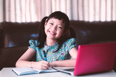 Cute asian little child girl studying  online lesson at home, social distance during quarantine, online education conceptの写真素材