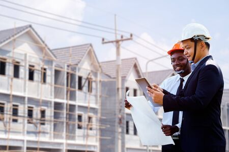 Asian and African architect engineer two expertise team plan with a building in background.の写真素材