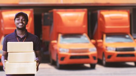 Smile african man postal delivery courier man in front of car delivering packageの写真素材