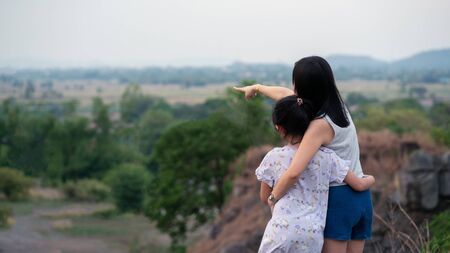 Mother and daughter looking to the view on the top of mountainの写真素材