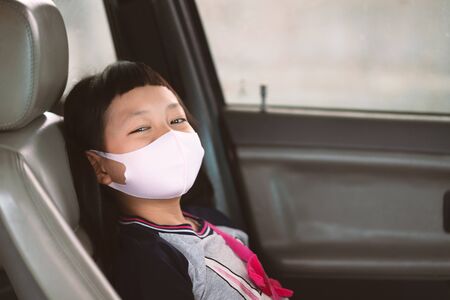 Asian little girl in a face mask from a car window. Hygiene mask protection coronavirus or covid-19の写真素材