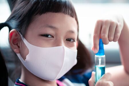 Little child girl wear face mask and holding sanitizer prevent virus and plague infection, prevent covid-19 virusの写真素材