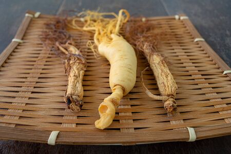 Fresh and dry ginseng on bamboo weave with the wood background.の写真素材