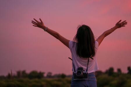 Portrait of beautiful freedom asian woman with holding medium format film camera with colorful sunset sky backgroundの写真素材