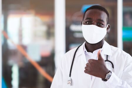 African doctor wear face mask and holding stethoscope with kind and smilingの写真素材