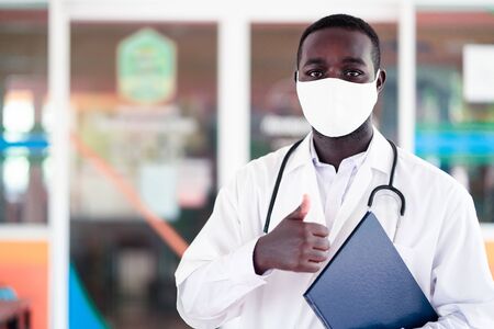 African doctor wear face mask and holding stethoscope and report bookの写真素材