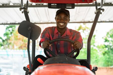 African farmer driving tractor in farm during harvest in countryside. Agriculture or cultivation conceptの写真素材