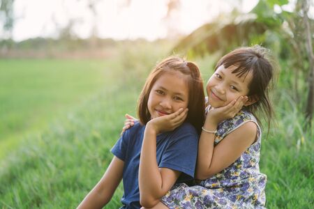 Happy little child girlfriends in green  fieldの写真素材