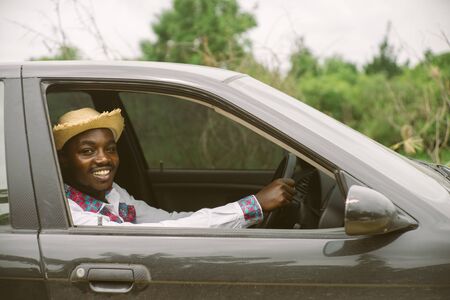 African man driver smiling while sitting in a car with open front windowの写真素材