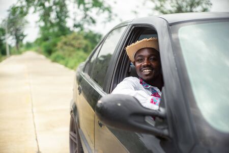 African man driver smiling while sitting in a car with open front windowの写真素材