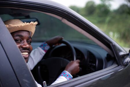 African man driver smiling while sitting in a car with open front windowの写真素材