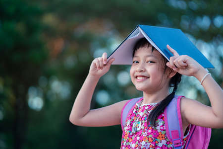 Smile little school girl holdind a book  with backpack.Back to school concept