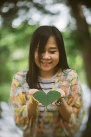 Woman holding a beautiful heart green leafの写真素材