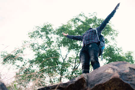 Freedom african man traveler standing on the top of the cliff and with backpackの写真素材