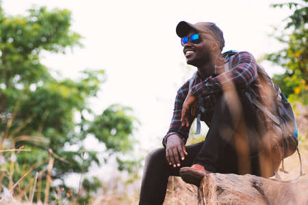 African man traveler sitting on the top of moutain with backpackの写真素材
