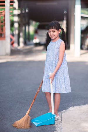 Smile asian little girl sweeping with broom and dustpan in the houseの写真素材