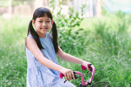 Asian little girl riding her bicycle outside with smile and happyの写真素材