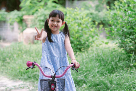 Asian little girl riding her bicycle outside with smile and happyの写真素材