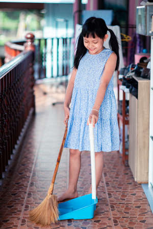 Smile asian little girl sweeping with broom and dustpan in the houseの写真素材