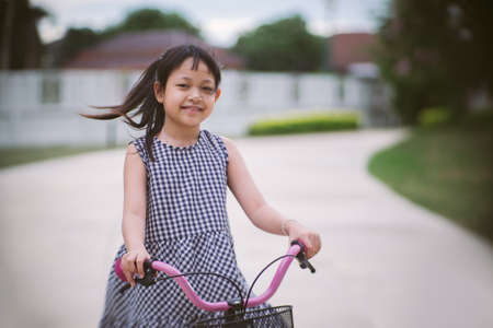 Asian little girl riding her bicycle outside with smile and happy.Vintage styleの写真素材