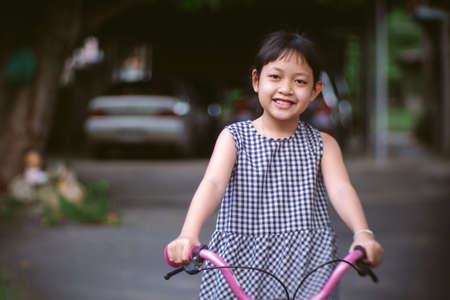 Asian little girl riding her bicycle outside with smile and happy.Vintage styleの写真素材