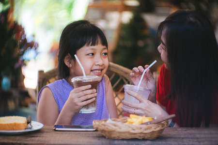Asian mother and daughter drinking and smiling with happinessの写真素材