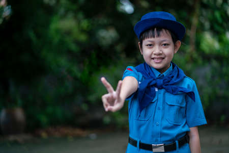 Beautiful uniform scout girl standing and showing fingers sign with happy and smileの写真素材