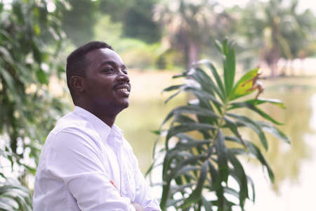 African business man in white shirt looking and thinking in green natureの写真素材