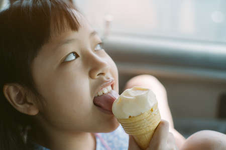 Happy asian little girl eating ice cream with smile in carの写真素材