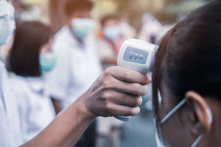 Hand holding Infrared thermometer gun forehead temperature test to check student for protect virus...
