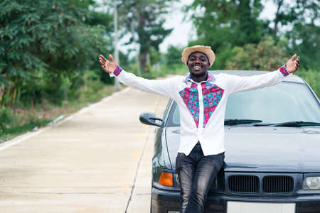 African man smiling while sitting on the front of a carの写真素材