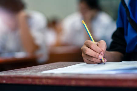 Students writing and reading exam answer sheets exercises in classroom of school with stress