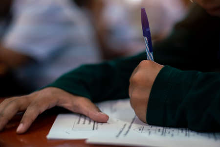 Close up Students writing and reading exam answer sheets exercises in classroom of school with stress.の写真素材