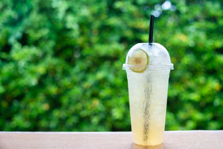 Glasses with lemonade in summer greenery background of a wooden tableの写真素材