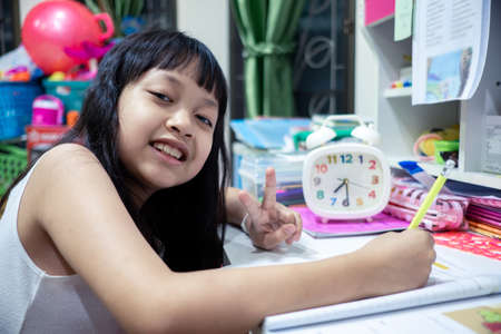 Asian little child girl doing her homework with smile and happyの写真素材