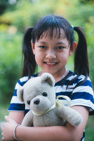 Smile little child girl hugging teddy bear with loveの写真素材