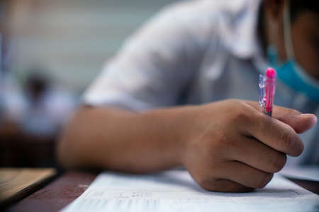 Students writing and reading exam answer sheets exercises in classroom of school with stressの写真素材