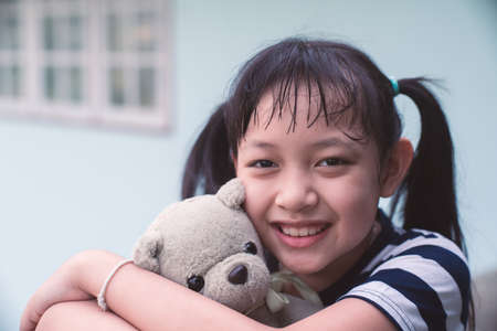 Smile little child girl hugging teddy bear with loveの写真素材