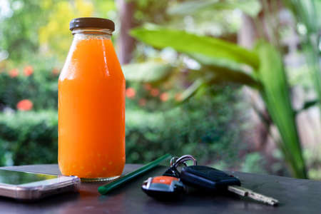 Freshly squeezed orange juice  in a bottle with smart phone and keysの写真素材