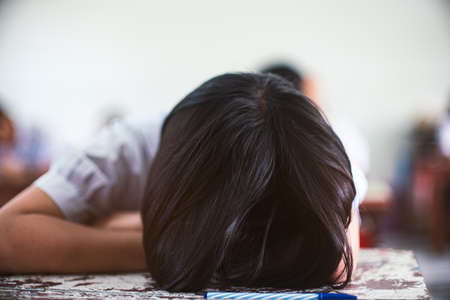 Tired uniform student sleeping in a exam test classroomの写真素材